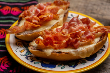 Mexican molletes with bacon and pico de gallo sauce on wooden background
