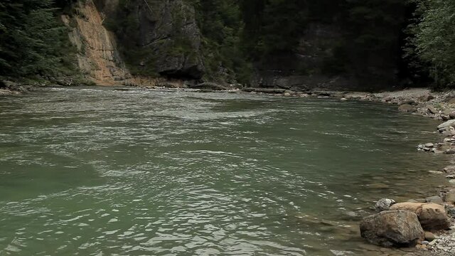 Schlucht mit Gebirgsfluss mit gr&uuml;nem Wasser und Wald sowie Felsen im Hintergrund
