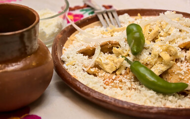 Side view of traditionals mexicans  chilaquiles with chicken, onion, grated cheese and a cup of coffee. Spicy food for drunks. Mexican food. Selective focus.