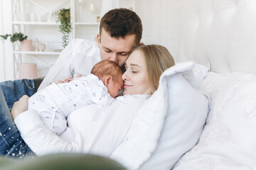 Fototapeta premium Happy family with newborn baby on the bed in room