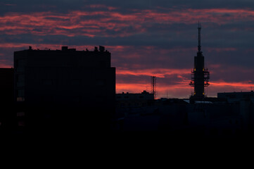 A silhouette of a tall telecommunication/broadcasting tower against the vivid red sky on a cloudy summer evening.