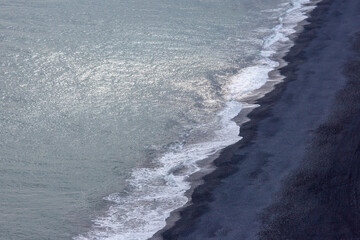 Fototapeta premium Waves of the Atlantic ocean fall on the black sand of the beach of Iceland from a height