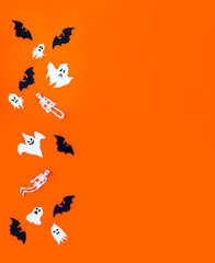 Black paper bats, white ghosts and flying rubber skeletons on orange cardboard. Background for Halloween, copy space
