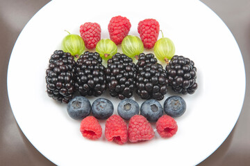 berries raspberries, blueberries, gooseberries and blackberries on a white plate. useful vitamin healthy food fruit. healthy vegetable breakfast
