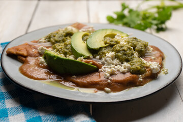 Mexican enfrijoladas with green sauce on white background