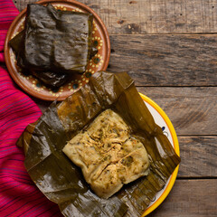 Mexican tamales in banana leaves on wooden background