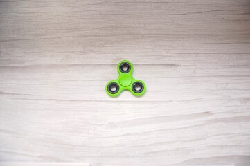 Green fidget spinner gadget isolated on grey wooden table. Background.