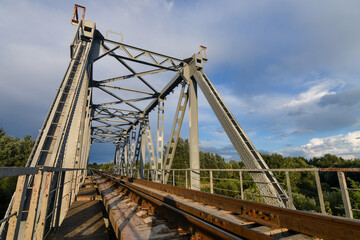 Fototapeta premium Big metal railway bridge over the river at sunset in summer.
