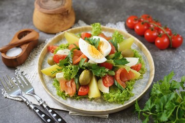 Salad with smoked salmon, lettuce, cherry tomatoes, olives, eggs and potatoes.