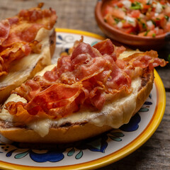 Mexican molletes with bacon and pico de gallo sauce on wooden background