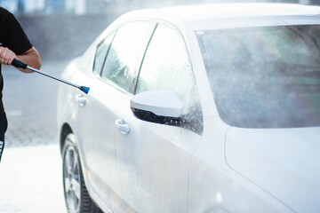 Summer car wash. Cleaning the car using high pressure water. Car wash with soap. Close up concept. Security measures during the epidemic. Concept disinfection and antiseptic cleaning. Car wash.