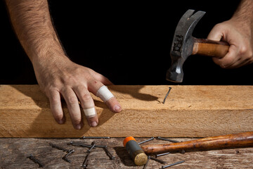 A craftsman hammering bent nail with difficulty