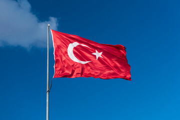 Turkish flag waving in blue sky.
