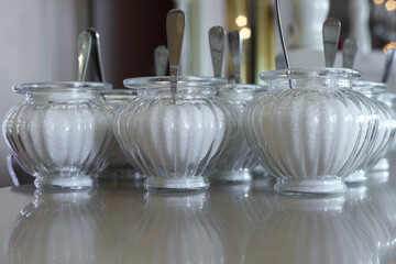 Glass sugar bowls with sugar are on the table