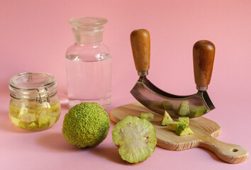 Osage green Apple and a blackboard with sliced fruit for the manufacture of medicinal tinctures. Horizontally on a pink background