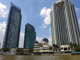 Fototapeta na wymiar Some tall buildings on the shore of the river in Bangkok under sunny day