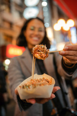 Mujer ofreciendo un delicioso takoyaki, tentempié tradicional de pulpo japonés