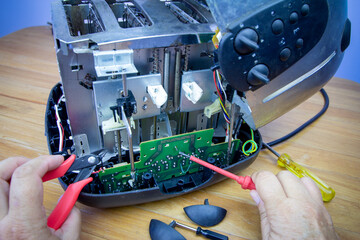 Hands of consumer repairing a toaster with tools. Reduce waste by repairing household appliances....