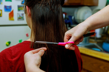 Mom cuts hair girl with scissors at home hairstyle