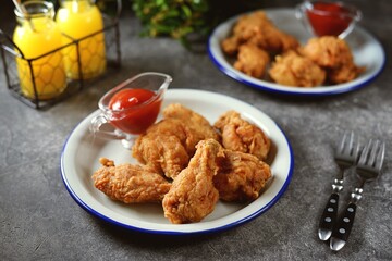 Delicious homemade deep fried breaded chicken wings with tomato sauce on a gray background.