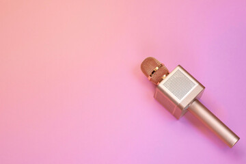Gold karaoke microphone on pink background, gradient, top view