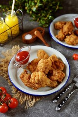 Delicious homemade deep fried breaded chicken wings with tomato sauce on a gray background.