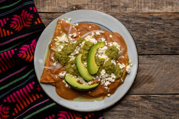 Mexican enfrijoladas with green sauce on wooden background