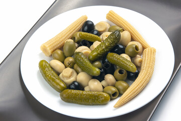 Olives, pickled cucumber, mushrooms and corn in a salad on a plate. food and vegetables. diet and weight loss