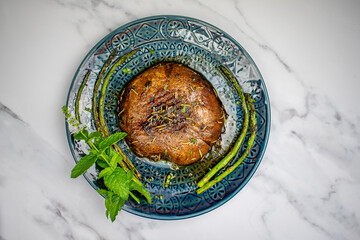 Grilled Portobello Mushroom with asparagus marinated in balsamic vinegar, soy sauce decorated with mint leaves in a blue dish
