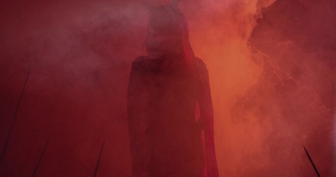 Silhouette of a female demon with long horns moving in red smoke, 4k