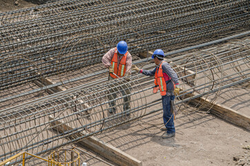 Construction workers laying the foundation with iron rods
Huge metal mesh assembled with steel...