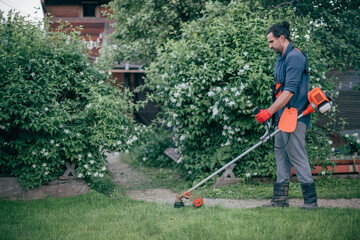 A man mows the grass with a hand mower in the garden