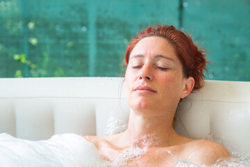 Pretty natural redheaded woman relaxing in her jacuzzi