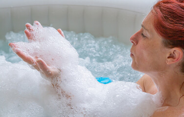 Fototapeta premium Pretty natural redheaded woman relaxing in her jacuzzi