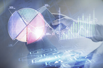 Double exposure of man's hands holding and using a digital device and forex graph drawing. Financial market concept.