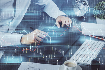 Double exposure of man's hands holding and using a phone and financial graph drawing. Analysis concept.