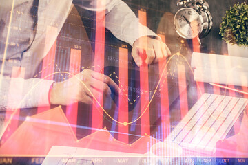 Double exposure of man's hands holding and using a phone and financial graph drawing. Analysis concept.