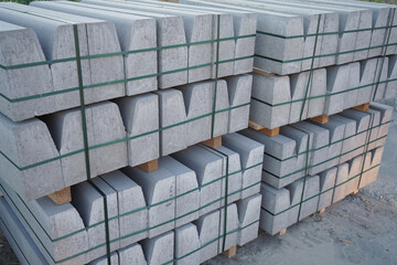 Concrete curbs on wooden pallets stand on the street during street repair. Road works, sidewalk repair.