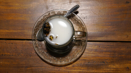 A glass of hot ginger milk on a wooden table. A special drink from Indonesia, pure milk mixed with grilled ginger