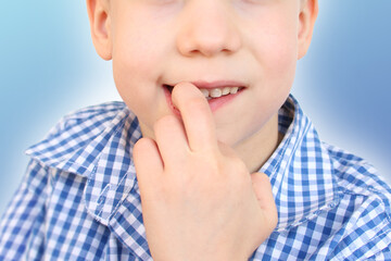 boy, kid nibbles and bites a nail on his hand, close-up, the concept of psychological disorder, stress, bad childhood habits
