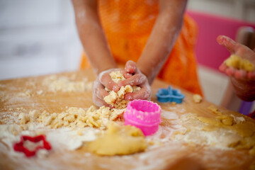 Obraz na płótnie Canvas Child's hands holding the dough for modeling on a cutting Board with colorful cookie cutters