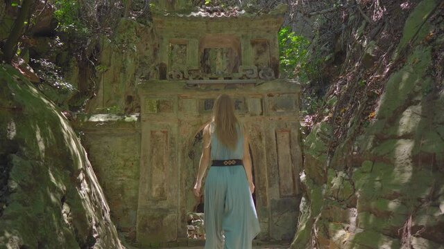 A young woman tourist visits the The Marble mountains a complex of Buddhist temples, famous tourist destination in the city of Da Nang, central Vietnam. She walks through old gates to the biggest cave