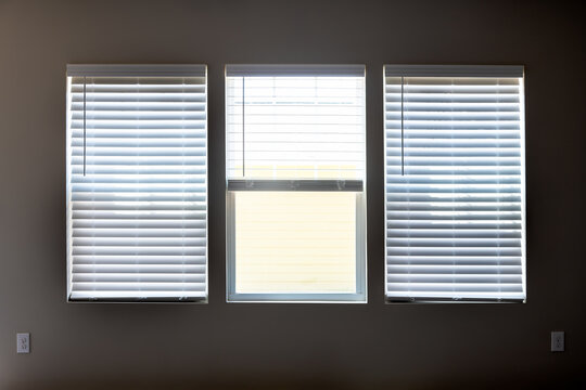 Three Windows With Closed Modern White Wood Faux Window Blinds As Background.