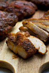 Baked chicken thigh with a herb and spice rub. On a wooden cutting board, cut into slices. 