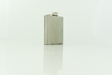 Silver hipflask, viewed from the front, on a white background, with reflections, landscape orientation 