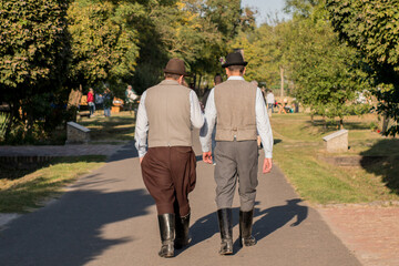 Hungarian men dressed in folk costumes are talking and walk away 