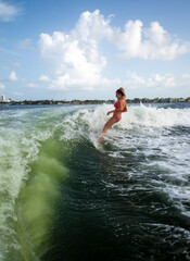 Surfer girl falling in to the water under blue sky wearing bright bikini