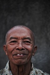 smiling indonesian senior man with bald head on blurry background