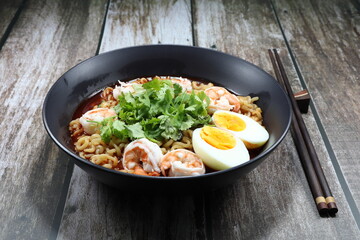 Traditional spicy soup of noodle menu topping with boiled peeled shrimp, chicken egg and coriander in the bowl. Famous hot and chilly soup menu in Asia restaurant. 