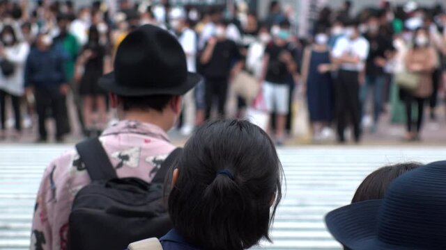 SHIBUYA, TOKYO, JAPAN - AUG 2020 : Back shot and crowd of people wearing surgical mask to protect from Coronavirus (COVID-19) at Shibuya Crossing. Shot in day time, hot summer season. Slow motion.